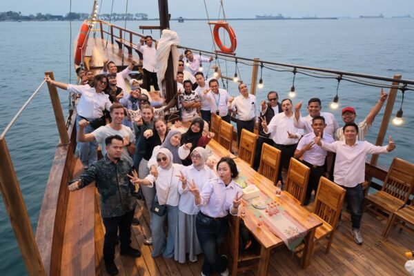 Rombongan gathering berpose di dek kapal pinisi saat sunset di perairan Makassar