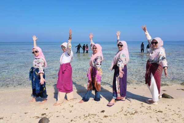 Wisatawan berpose di pantai pasir putih dengan air laut jernih saat Morning Sailing Makassar